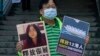 Hongkongi aktivista áll a kínai kormány képviselete előtt, jobb kezében Zhang Zhant támogató transzparensével, Hongkogban, 2020. december 28-án. 