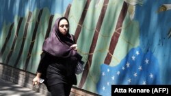 A woman walks by a mural on the wall of the former U.S. Embassy in Tehran in August 2018.