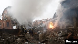 მეხანძრეები მუშაობენ საცხოვრებელ კორპუსთან, რომელიც რუსეთის მიერ უკრაინაზე თავდასხმისას, დრონებითა და რაკეტებით მიტანილი იერიშის შედეგად დაზიანდა. კიევი, უკრაინა, 22 თებერვალი, 2026 წელი. REUTERS/ვალენტინ ოგირენკო.