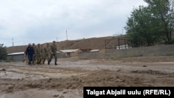 Сел жүріп өткен елдімекенде келе жатқан әскери киімдегі адамдар. Созақ ауданы, Қырғызстан, 21 шілде 2021 жыл.