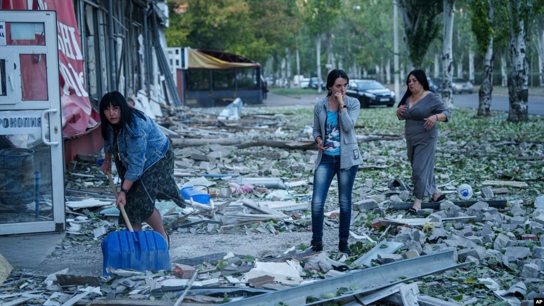 Oamenii curăță molozul din fața unui bloc de locuințe avariat după un atac aerian rusesc la Kramatorsk, în regiunea Donețk din Ucraina, pe 25 septembrie.