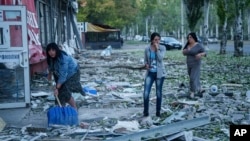 People clear the rubble in a front of a residential building that was heavily damaged after a Russian air strike in Kramatorsk in Ukraine's Donetsk region on September 25. 