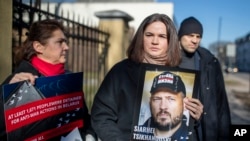 Belarusian opposition leader Svyatlana Tsikhanouskaya holds a portrait of her imprisoned husband, Syarhey Tsikhanouski, during a protest in Vilnius on March 8, saying she had not heard from him in 481 days.