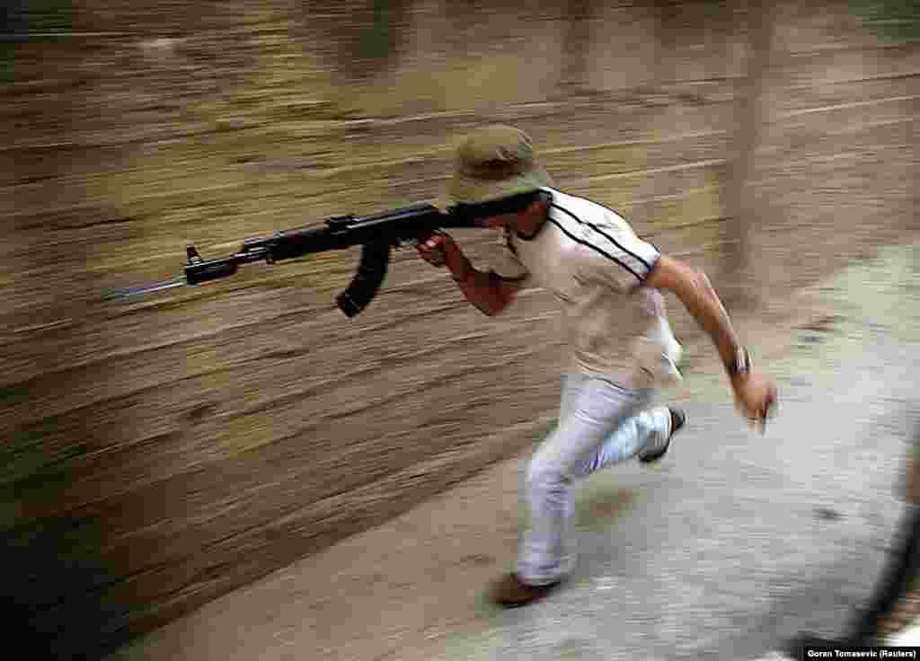 A Palestinian gunman runs to take up a position in the Jenin refugee camp during an assault by the Israeli military in June 2002. The picture was taken the same day that a Palestinian suicide bombing killed 17 people.