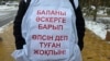 Қазақстан армиясында реформау жүргізуді талап етіп, үкімет үйінің алдына келіп тұрған адамдардың бірі сырт киіміне тағып алған жазу. Астана, 10 қараша, 2025 жыл.