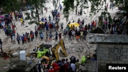 Stanovnici gledaju radnike kako raščiščavaju područje zahvaćeno tropskom olujom Laura, u Port-au-Prince, Haiti 23. augusta 2020. Casares