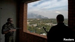 Pro-Russian rebels watch from a building as smoke rises near the Donetsk airport after recent shelling on September 23.