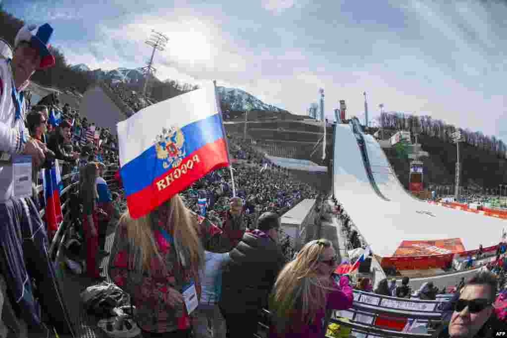 Russian nordic-combined fans wave flags during the individual competition at the RusSki Gorki Jumping Center.
