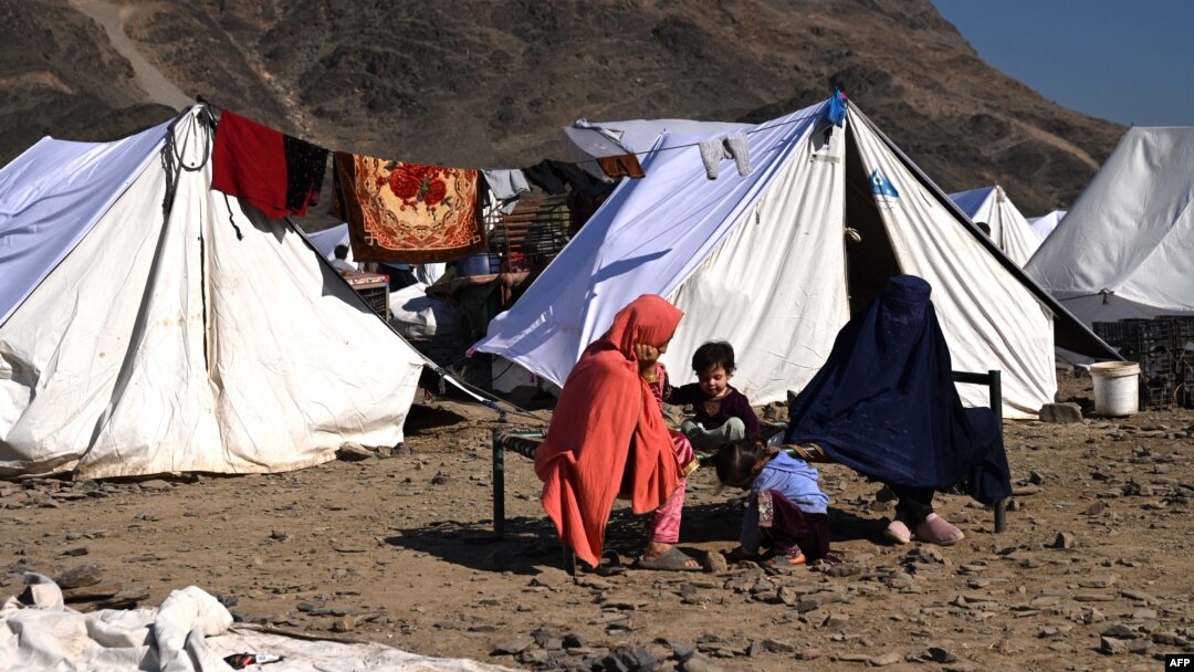 Afghan migrants in Nangarhar Province sit outside tents at a makeshift camp upon their arrival after being returned from Pakistan on November 12. 