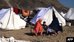 Afghan migrants in Nangarhar Province sit outside tents at a makeshift camp upon their arrival after being returned from Pakistan on November 12. 