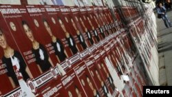 A woman walks past election posters in the center of Tbilisi.