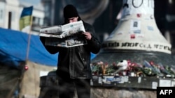 A man reads a newspaper on Kyiv's Independence Square on February 24. Demonstrators have begun to trickle away from the tent camp, seemingly eager to return to a normal routine after weeks of freezing vigils and pitched battles with riot police and thugs.