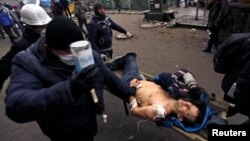 Antigovernment protesters carry an injured man on a stretcher after clashes with riot police on Independence Square in Kyiv on February 20.