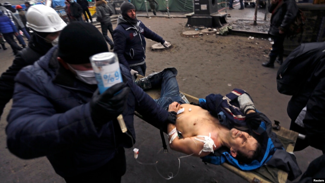 Antigovernment protesters carry an injured man on a stretcher after clashes with riot police on Independence Square in Kyiv on February 20.