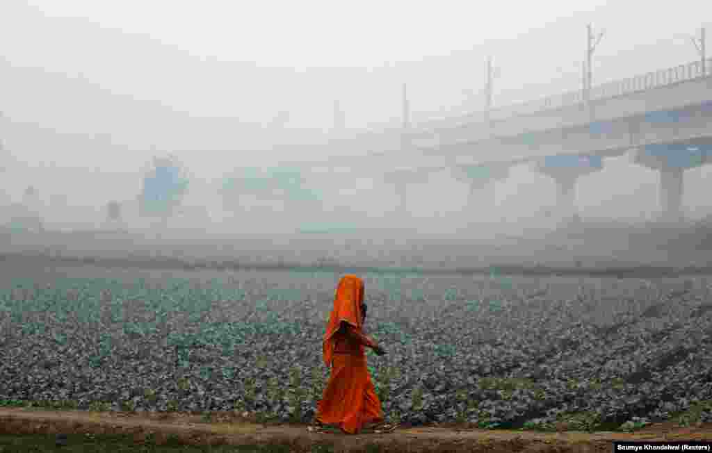 A woman walks across a field on a smoggy morning in New Delhi, India. (Reuters/Saumya Khandelwal)