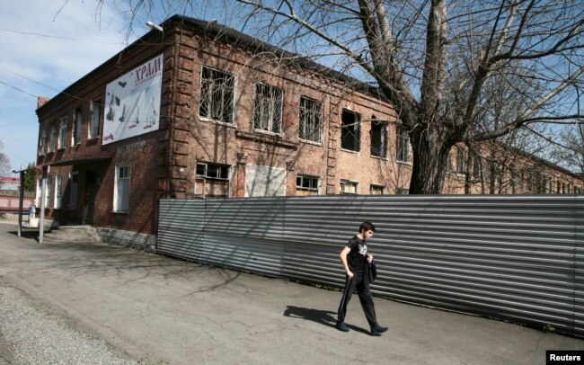 Kezinde terrorşılar basıp alğan Beslan qalasınıñ mektebi janınan ötip bara jatqan adam. 13 säuir 2017 jıl.