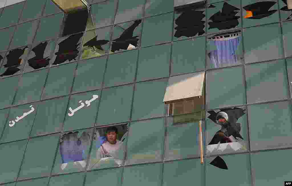 Men peer through broken windows following a suicide attack in Ghazni, Afghanistan, on September 4. A Taliban truck-bomb attack on a government compound killed 13 security personnel and left at least 60 other people wounded. (AFP/Rahmatullah Alizadah)