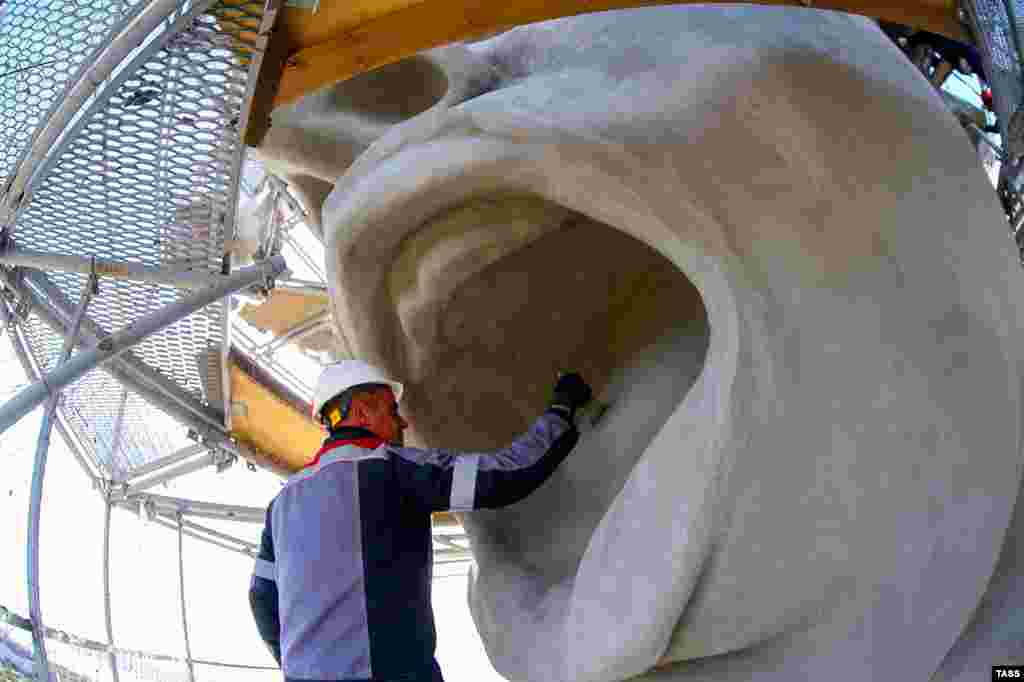 A worker brushes the statue’s tongue. Weathering of the monument has been an ongoing issue, with the harsh climate of southern Russia leading to chips of concrete flaking off. 