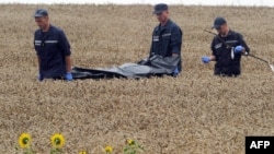 Ukrainian rescue workers carry the body of one of the 298 victims on a stretcher through a wheat field at the site of the MH17 crash on July 19, 2014.