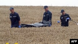 Ukrainanyň halas ediş toparynyň işgärleri MH17 uçar heläkçiliginde pida bilanlaryň jesetlerini daşaýarlar.