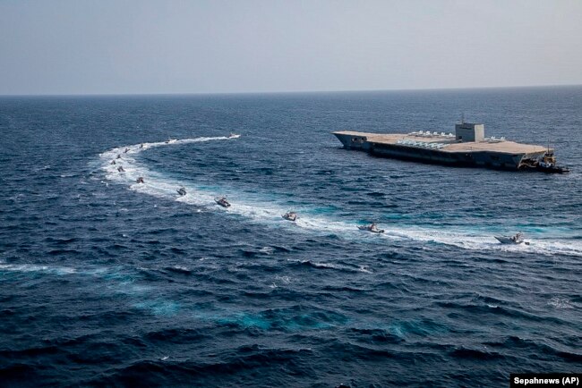 Iranian speedboats circle around a replica aircraft carrier during a military exercise in the strategic Strait of Hormuz on July 28.