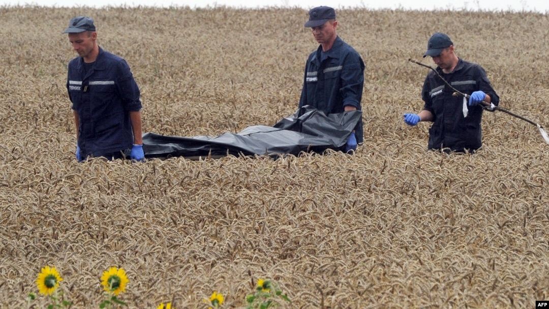 Ukrainian rescue workers carry the body of one of the 298 victims on a stretcher through a wheat field at the site of the MH17 crash on July 19, 2014.