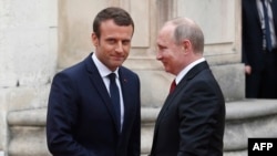 Russian President Vladimir Putin (right) is welcomed by newly elected French President Emmanuel Macron at the Palace of Versailles in late May.