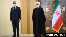 Iranian President Hassan Rohani, right, welcomes Iraqi Prime Minister Mustafa al-Kadhimi as they wear protective face masks to help prevent spread of the coronavirus, during an official arrival ceremony, in Tehran, July 21, 2020