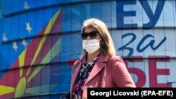 Жена со заштитна маска поминува пред Делегацијата на Европската унија во Скопје