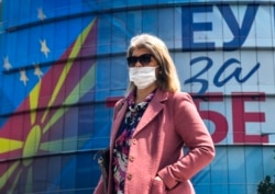A woman walks in front of the EU office decorated with Macedonian and EU flags and their logo "EU for You" in Skopje.