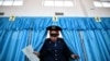 Сотрудник полиции выходит из кабинки для избирателей в день парламентских выборов в Казахстане. Март 2016 года.