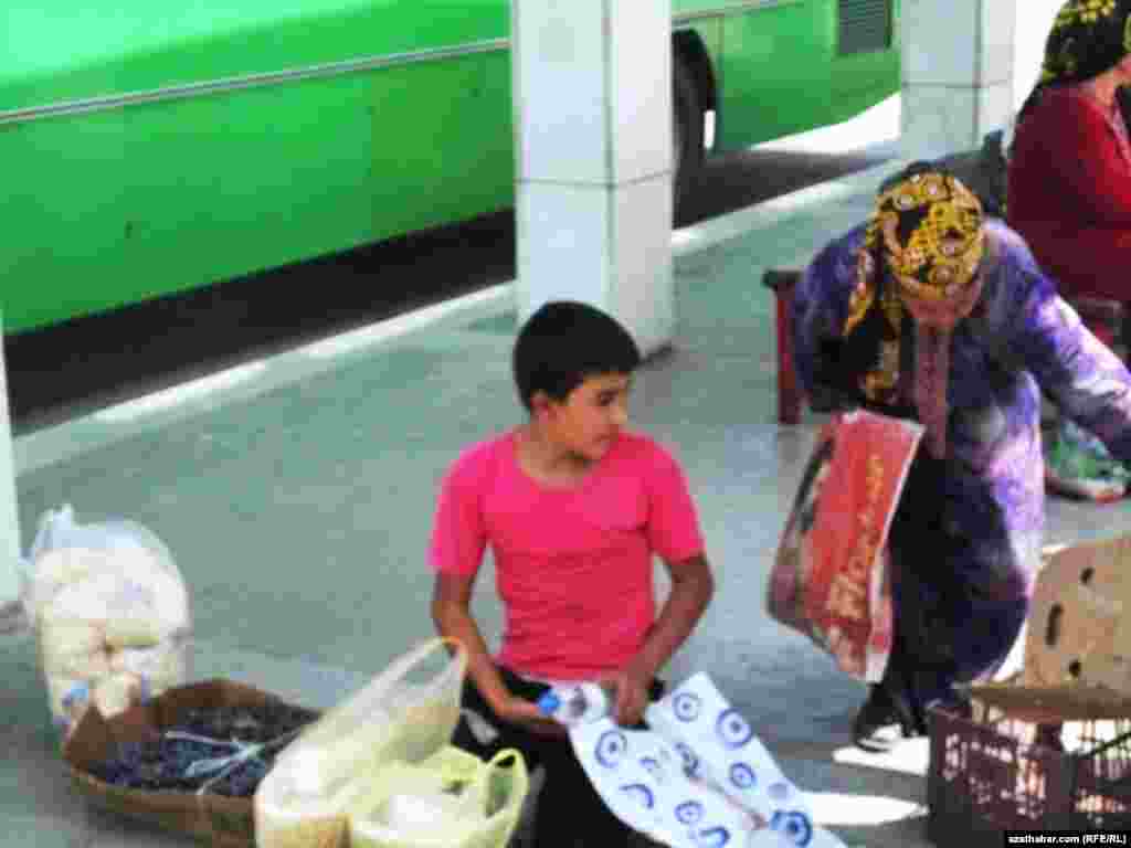 Köçäniň gyrasynda söwda edip oturan bir oglan