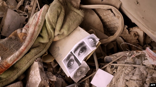 Pictures of people's eyes lie amid the rubble of a residential building that was hit in an Israeli strike, in Tehran