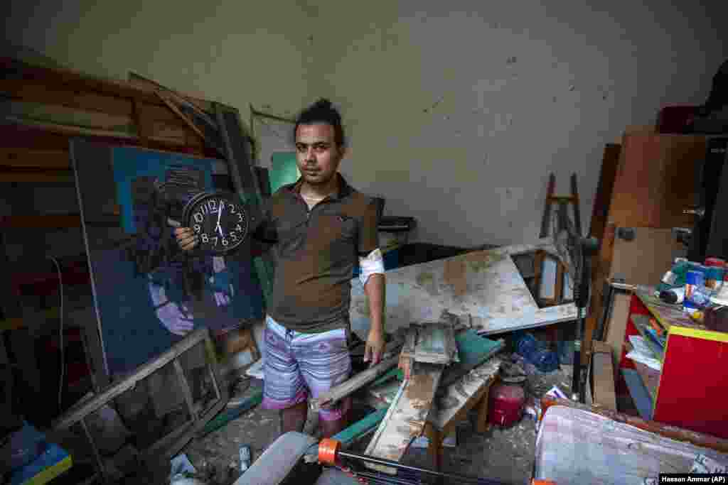 Hasan Al Armali, holds a wall clock that was stoped working at the time of the Tuesday's explosion in the seaport of Beirut, poses for a photograph at his bedroom inside his destroyed apartment, in Beirut , Lebanon, Thursday, Aug. 6, 2020. 