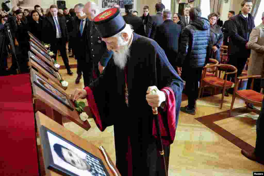 Mitropolit Crnogorske pravoslavne crkve Mihailo namješta cvijet ispod slike tokom komemoracije.