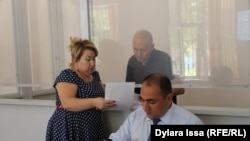 Обвиняемый в вымогательстве денег с полицейских гражданский активист Руслан Жанпеисов (за стеклом) и его адвокаты в суде по его делу. Шымкент, 26 сентября 2017 года.