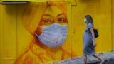 HONG KONG -- A pregnant woman wearing a face mask as a precautionary measure walks past a street mural in Hong Kong, on March 23, 2020