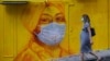 Беременная женщина в защитной маске проходит мимо уличной росписи в Гонконге. 23 марта 2020 года.