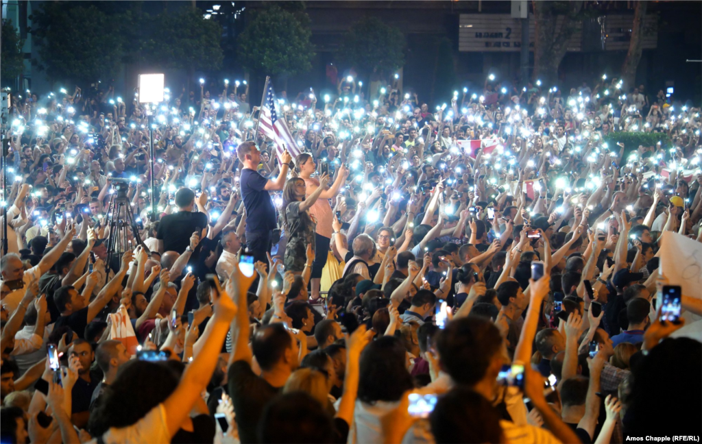Demonstrators hold their cellphones in the air as the Georgian national anthem is sung.&nbsp;