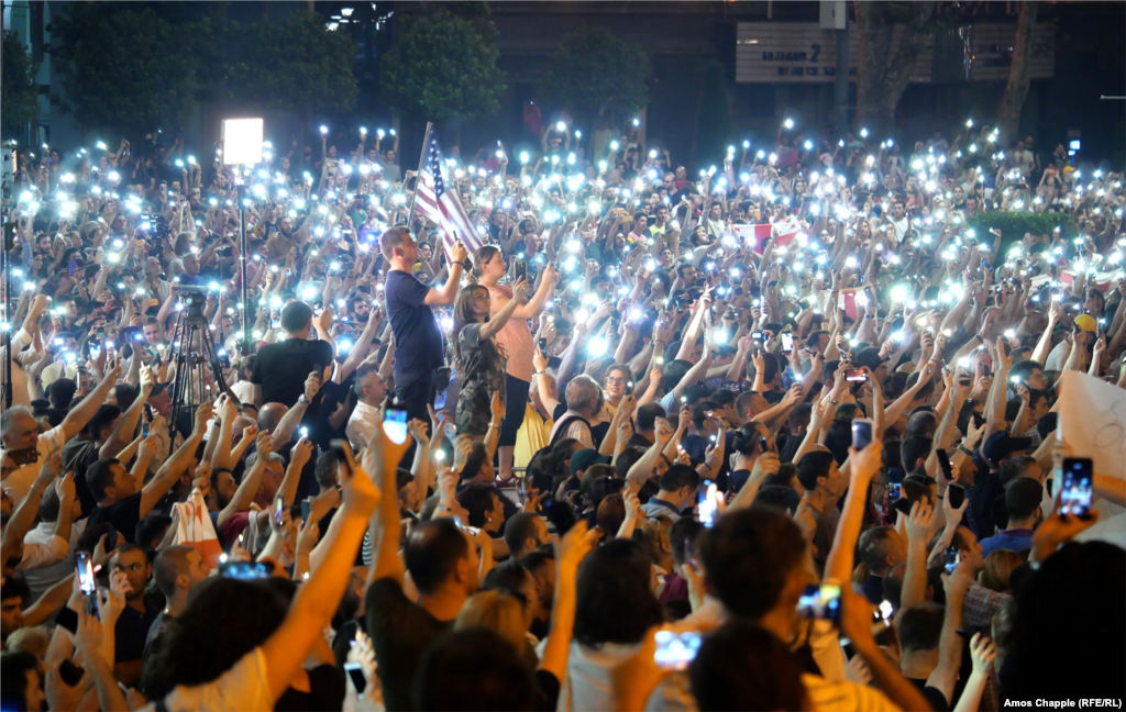 Demonstrators hold their cellphones in the air as the Georgian national anthem is sung. 