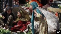 FILE: An Afghan girl, right, takes a brake who carries a sack containing waste items, as other girls sell vegetables, wait for customers at the market in Kabul.