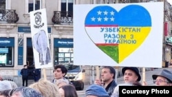 Плакат, объединяющий элементы флагов Узбекистана и Украины, с надписью: «Узбекистан вместе с Украиной». Митинг во Франции, 24 февраля 2026 года