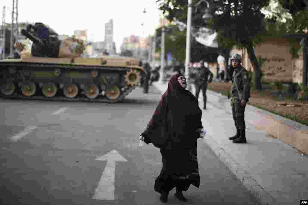 An Egyptian woman screams as she walks past soldiers standing guard in front of the Presidential Palace ahead of a planned demonstration by opposition supporters. (AFP/Marco Longari)