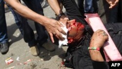 Antimilitary protesters help a wounded demonstrator during clashes in the Abbassiya district of Cairo on May 2.