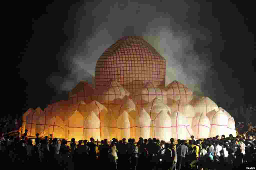 People launch a 30-meter-diameter paper lantern at the village of Xiapo in China's Hainan Province. The lantern, made of 72 smaller lanterns, was designed for a local ritual ceremony to mark the Chinese Hungry Ghost Festival. (Reuters/China Daily)