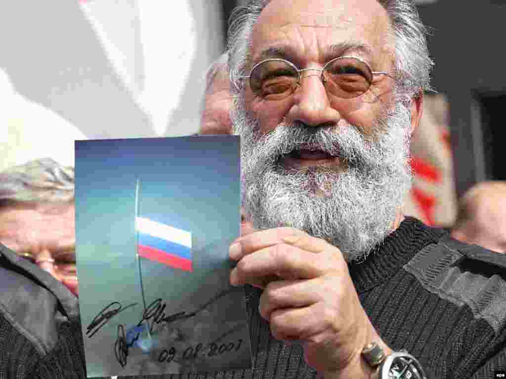Caption: epa01085667 The head of Russian expedition Arctic-2007 Artur Chilingarov holds the picture of Russian flag at the ocean bottom as the crew of the expedition arrive in Moscow airport Vnukovo-3 07 August 2007. best07