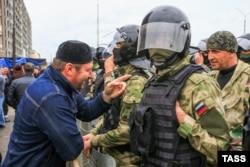 Бойцы ОМОНа и участник акции протеста против изменения границ между республиками Ингушетия и Чечня, 5 октября 2018 года