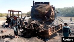 Police officers inspect the site of the September 2009 air strike in Kunduz, which had been ordered by a German commander who feared the Taliban could use the fuel tankers to carry out attacks.