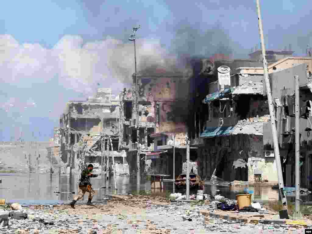 A National Transitional Council (NTC) fighter runs to take cover from incoming sniper fire during a battle in the Libyan city of Sirte on October 14. (Photo by Mohamed Messara)