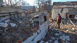 A man stands next to his destroyed car at the site of a residential area hit by a Russian missile strike in Kharkiv, Ukraine, March 31, 2023.